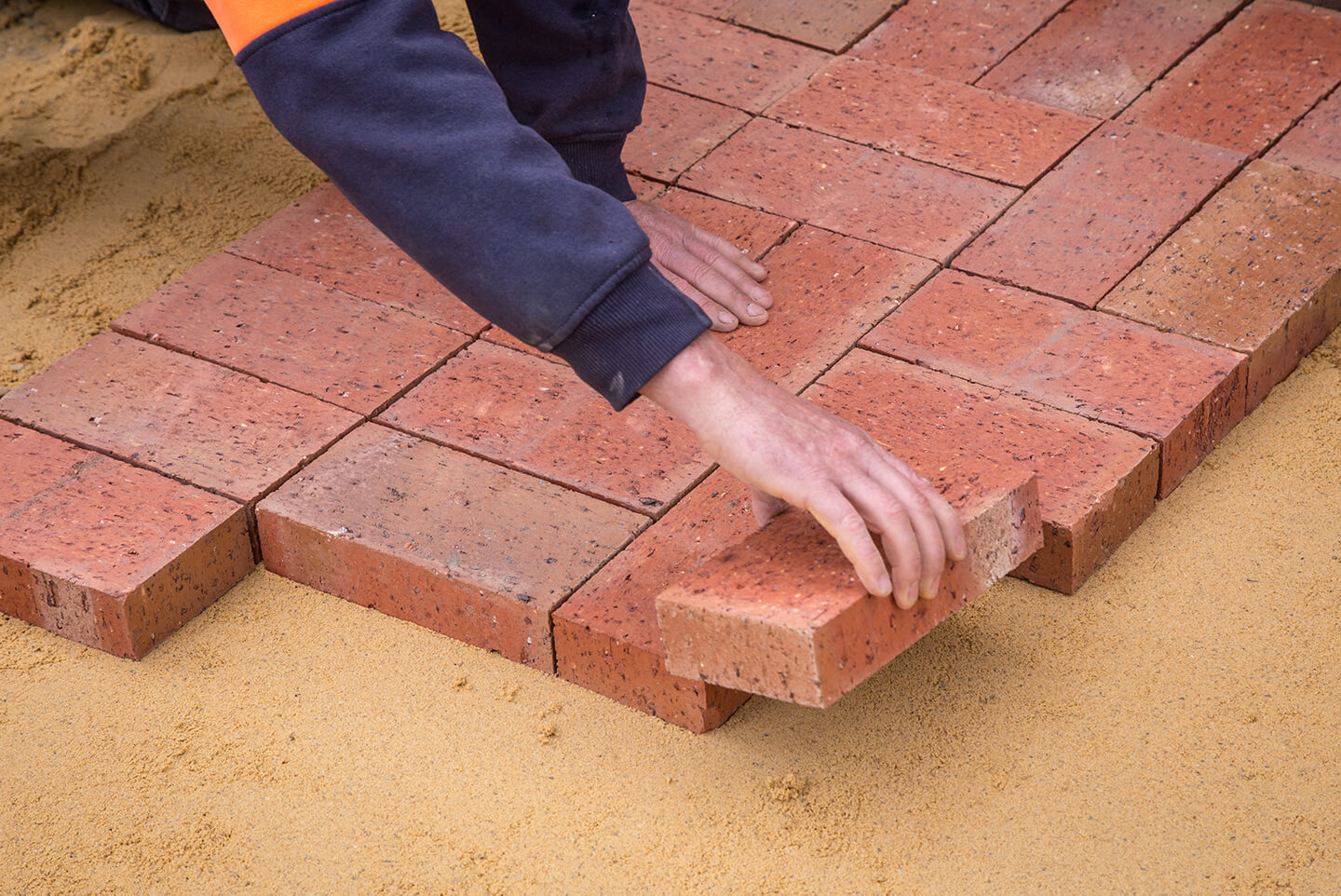 Article Banner Image - A photo of a hand placing a brick on the ground